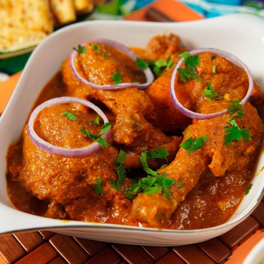 Chicken karahi plated with onion and coriander